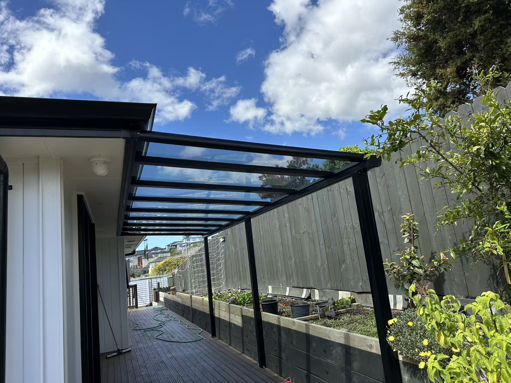 Black aluminium glass veranda over a garden deck in Auckland