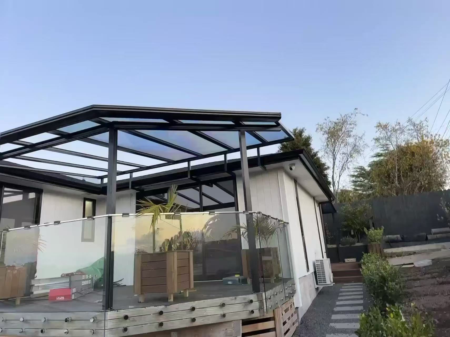 Glass roof pergola over a timber deck at dusk